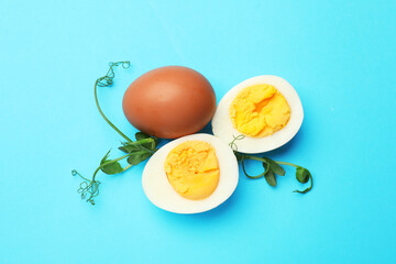 Boiled eggs and microgreens on light blue background, flat lay