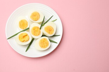 Boiled eggs and green onions on pink background, top view. Space for text