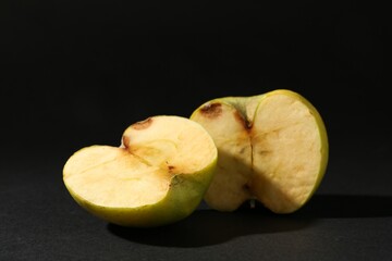 Halves of damaged apple on black background