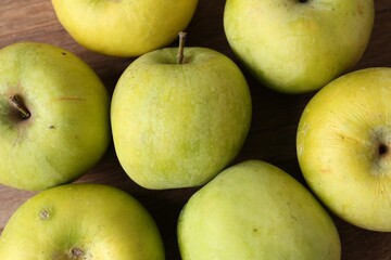 Many damaged green apples on wooden table, closeup