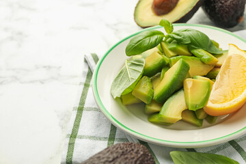 Tasty ripe green avocados, basil and lemon on white marble table, closeup. Space for text