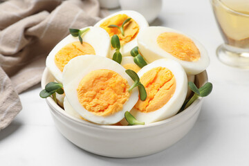 Halves of hard boiled eggs with microgreens on white table, closeup
