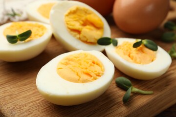 Halves of hard boiled eggs with microgreens on wooden table, closeup