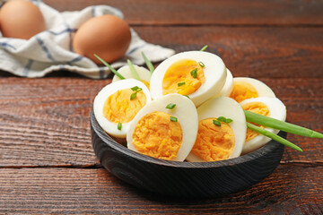 Halves of hard boiled eggs with green onions on wooden table, closeup