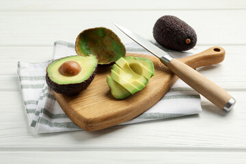 Tasty cut avocados and knife on white wooden table