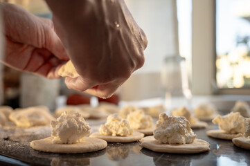 Forming dumplings, close-up of hands at work. Traditional Ukrainian dumplings with cottage cheese - step-by-step process of home cooking.