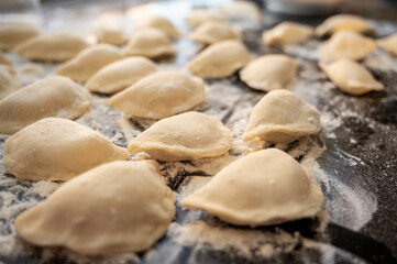 Raw varenyky on a black countertop, top view. The process of making Ukrainian varenyky with cottage cheese.