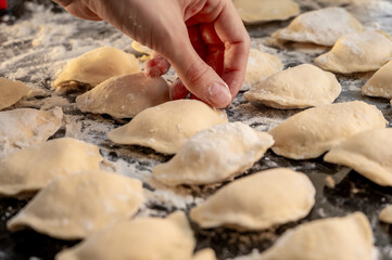 Raw varenyky on a black countertop, top view. The process of making Ukrainian varenyky with cottage cheese.