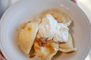 Serving ready varenyky with sour cream and fried onions. Step-by-step photo series demonstrating the traditional process of making Ukrainian varenyky with cottage cheese.