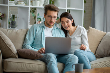 Fototapeta premium Couple browsing laptop together on couch
