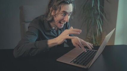 Excited Man Engrossed in Laptop Activity with Intense Facial Expressions and Rapid Typing, Featuring Energetic Mood and Warm Screen Glow