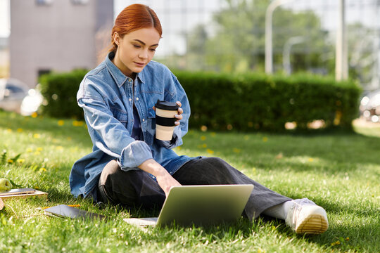 Red haired woman enjoying coffee while working on laptop in a sunny park setting