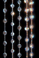 Close-up of sparkling crystal bead strands hanging vertically against a dark background, reflecting light with a shimmering and elegant glow