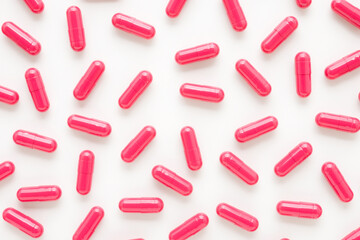 Red capsule pills for improve of iron level in blood on white table background. Medicine pattern. Closeup. Top down view.
