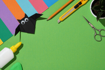 Creative workstation with colorful craft materials on green background with a handmade black...