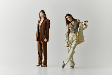 Stylish twin sisters showcasing unique fashion choices in a minimalistic setting