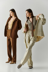 Stylish twin sisters captivating in elegant outfits striking a pose together
