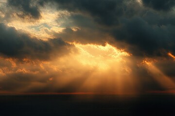 dramatic sunset with sun rays breaking through thick dark clouds over calm ocean water