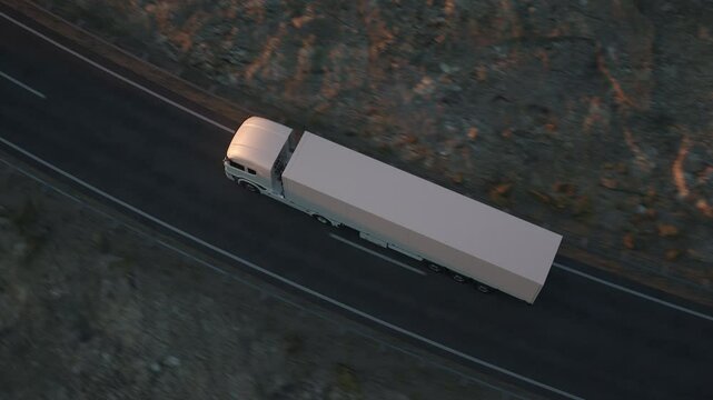 Top view of a white long distance semi truck with cargo trailer drives on a desert road into the sunset. Drone POV following the truck. 3d animation rendering.