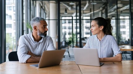 Fototapeta premium Man and woman working on laptops in modern office space