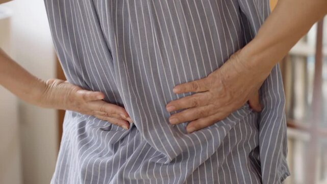 Close up of old woman hands grabing on hurt lower back