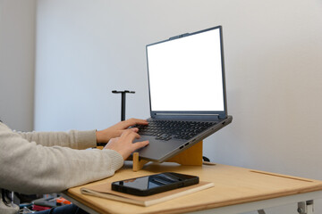 Unrecognizable female hands typing on a laptop with a blank screen at home