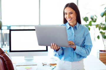 Professional businesswoman working on a laptop while smiling in a modern office environment
