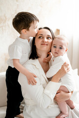 a mother with two children hugs and kisses, maternal love and care, a mother on maternity leave with young children at home, a mother and children