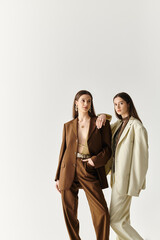 Stylish twin sisters showcase modern fashion with elegance and confidence in a minimalist setting