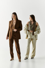 Stylish twin sisters showcasing unique fashion styles in a minimalist studio setting