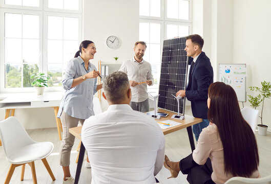 Businessman conducts a presentation on solar panels and renewable energy sources for a group of clients in an office setting. The focus is on promoting sustainable energy solutions.