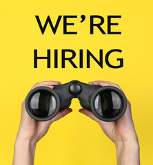We Are Hiring. Woman with binoculars on yellow background, closeup. Recruitment, human resources...