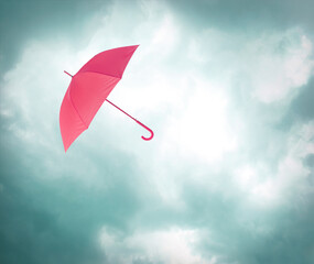 Pink umbrella flying in cloudy sky. Stormy weather