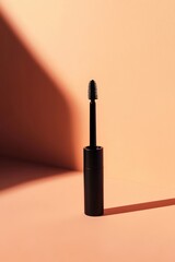 Black mascara wand against peach backdrop