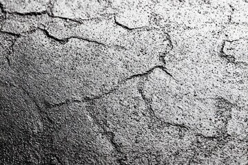 Obraz premium Close-up of cracked dry soil surface showing textured parched earth with varying shadows and light contrasts