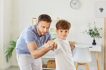 Fototapeta premium Portrait of a father and son engaged in martial arts training together at home. They practice fighting techniques, bonding through exercise and building strength during active workout.