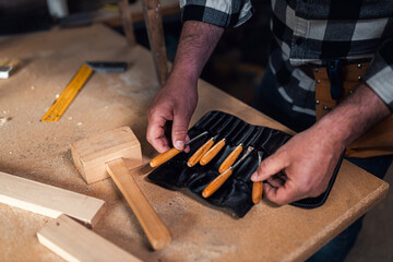 Close up of male carpenters hands choosing the carving tool.