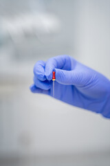 A trained medical professional is carefully handling a test tube inside a laboratory setting