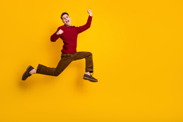 Happy Positive Young Man Jumping with Excitement on Yellow Background