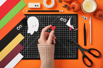 Cut out a heart from red paper. Autumn creativity from paper, make a loving ghost. Table for crafting from paper.