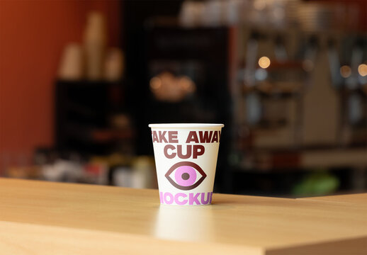 Blank takeaway cup mockup on a wooden counter ready for design.