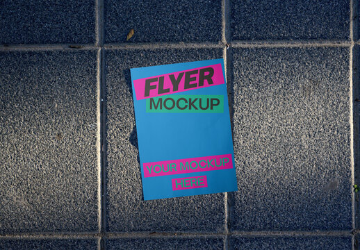 A flayer lies on the sidewalk in an urban area. PSD template mockup.