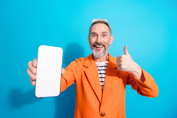 Charismatic man with dyed hair enthusiastically presenting a smartphone and showing thumbs up