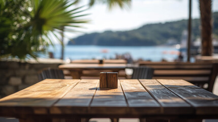 Bare wooden table set before a blurry seascape, typical of a coastal bar or restaurant