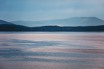 Cloudy and melancholic morning on the ferry to Vancouver. A moody seascape with calm waters, misty...