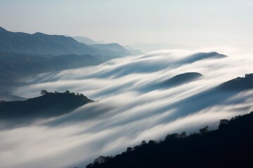 Low clouds rolling over the hills create a stunning wave effect, enhancing the surreal beauty of the tranquil landscape below