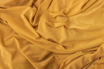 Elegant fabric texture in golden color with soft flowing folds and creases