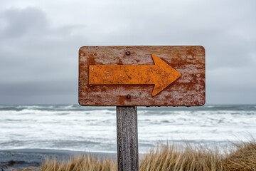 Rustic wooden sign with an orange arrow points right, at a beach with waves