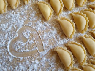 A floured board with dumplings and a hand drawn heart. Food background