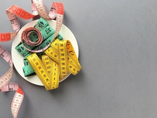 White plate with three colored measuring tapes on grey background